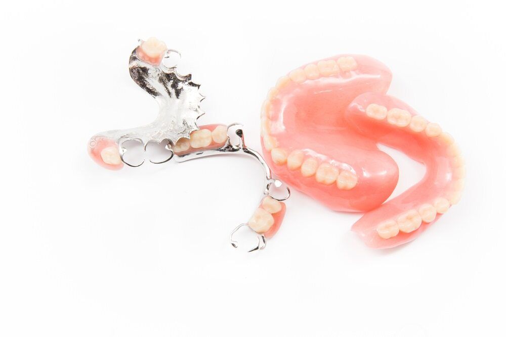 A Pair Of Dentures Laying On Top Of Each Other On A White Surface — Dentures Direct Taree-Rod Hinton In Taree, NSW