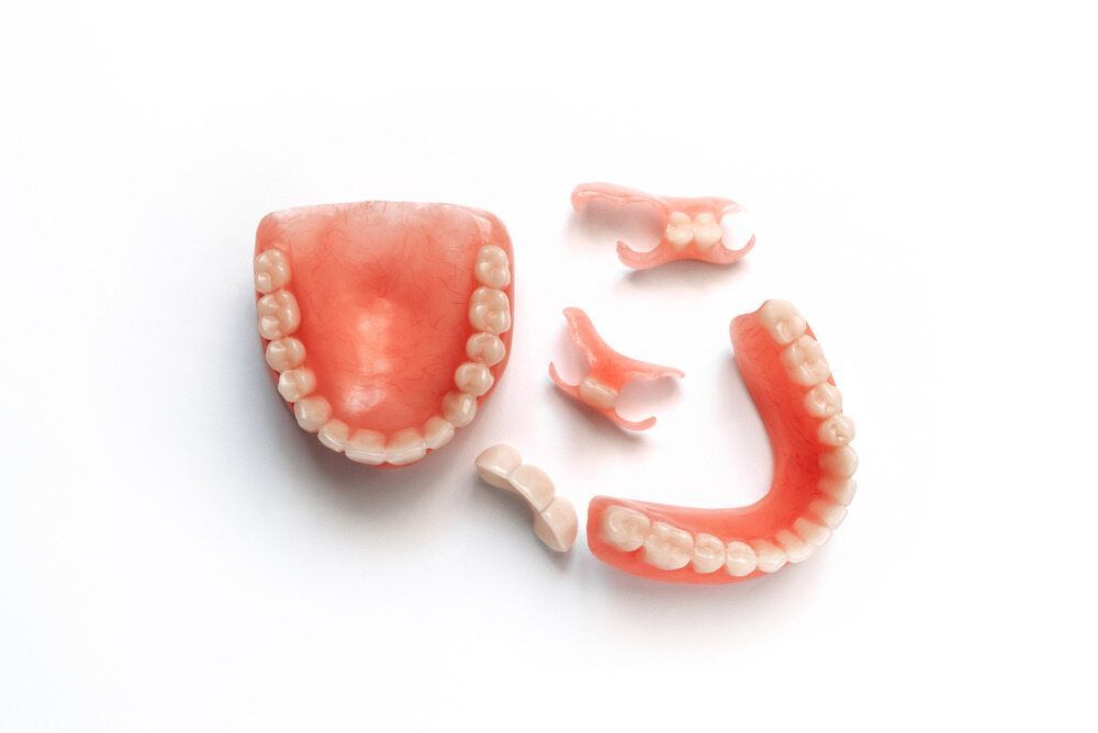 A Broken Denture Is Sitting On A White Surface — Dentures Direct Taree-Rod Hinton In Taree, NSW