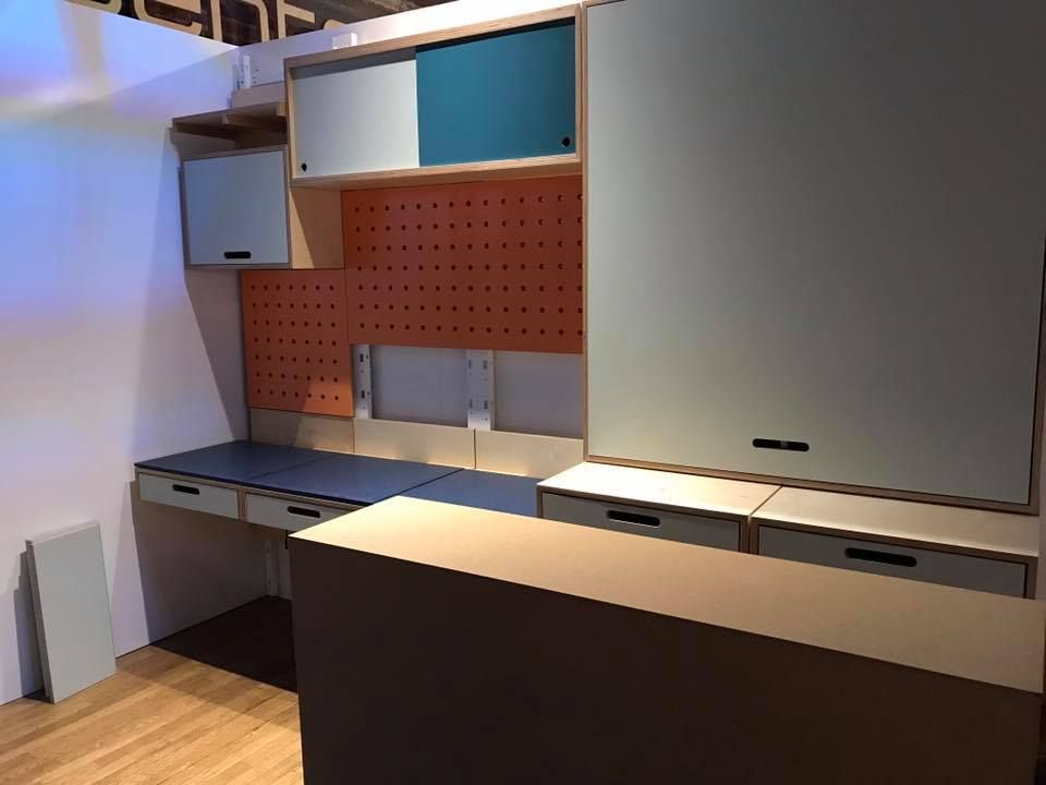 Built-in wooden desk unit with cabinets, drawers, and orange pegboard, in a room.