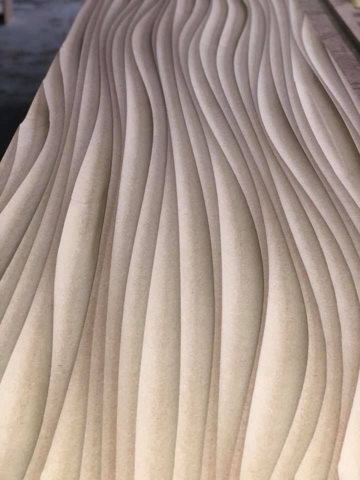 Sculpted wooden panel with flowing, vertical wave-like patterns.