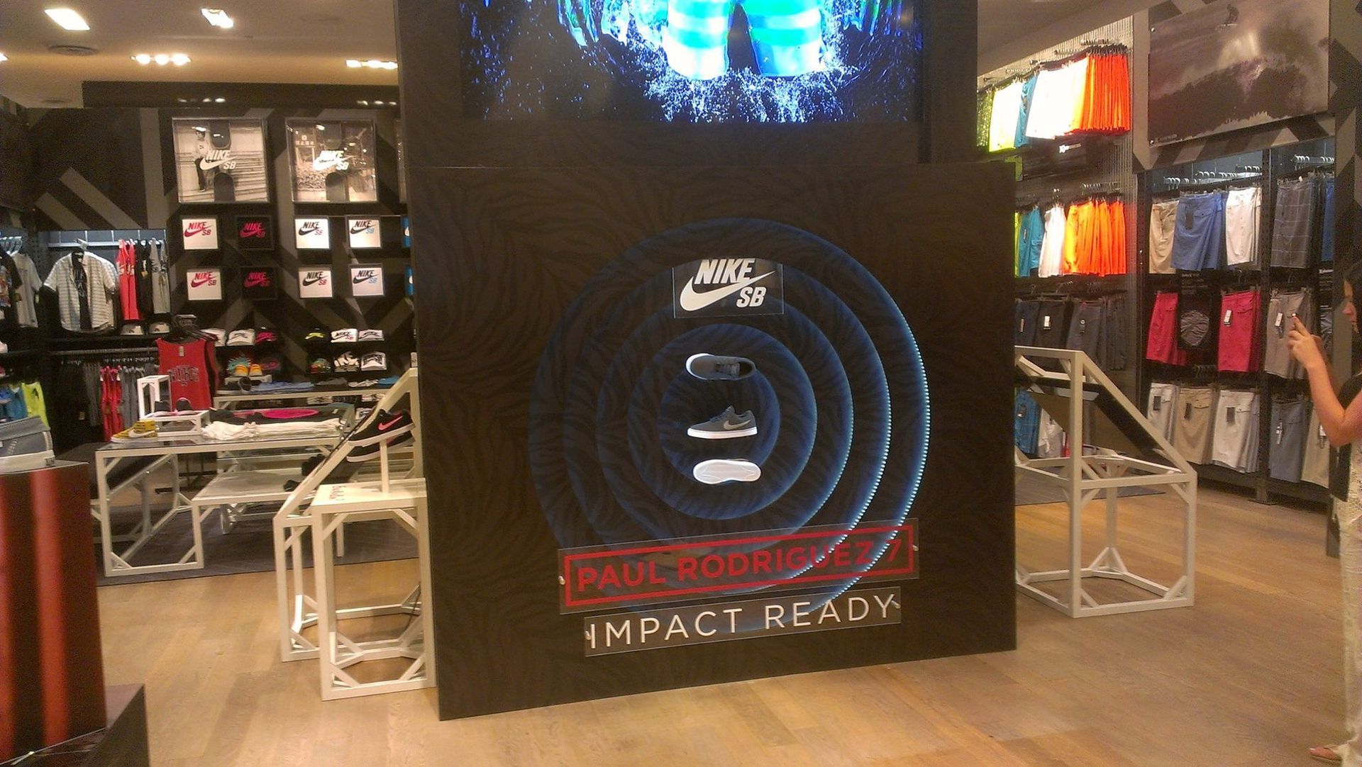 Nike shoe display in a store with a black background and neon blue spiral design, featuring sneakers.