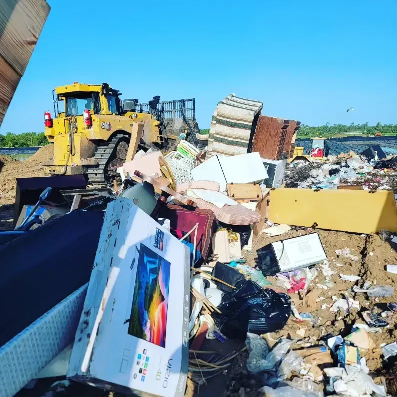 a box of a flat screen tv sits in a pile of trash