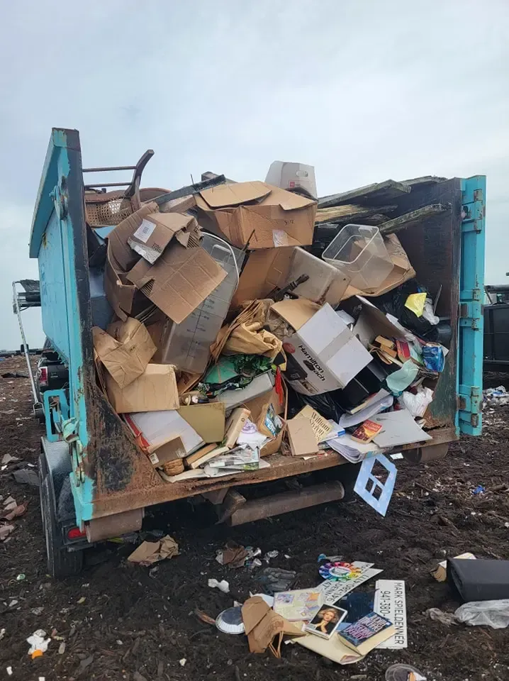 a dumpster filled with cardboard boxes and a sign that says 