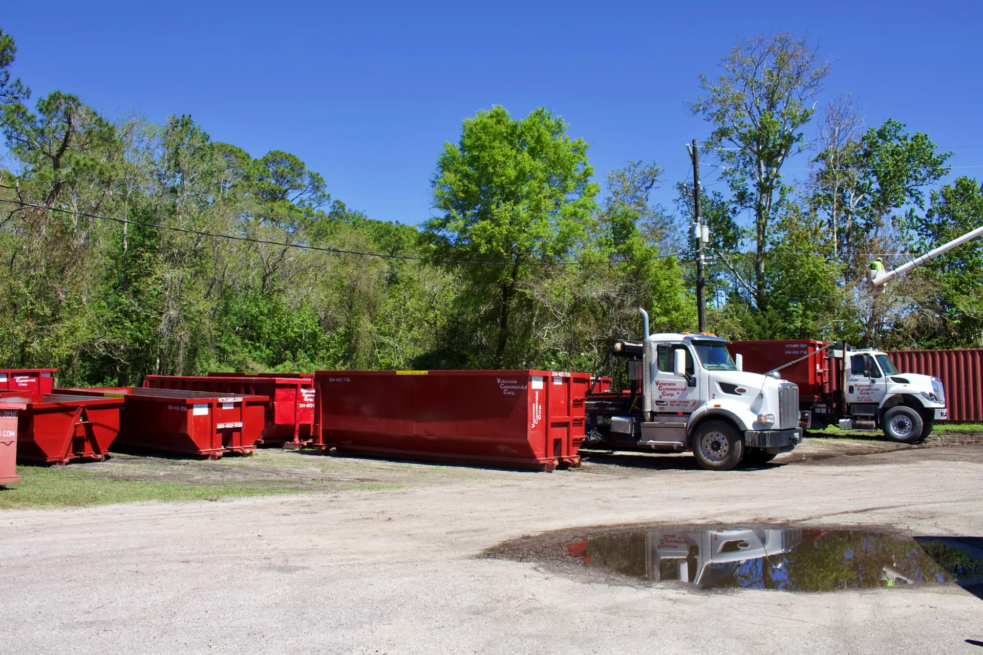 A dumpster is being towed by a dump truck in a driveway.