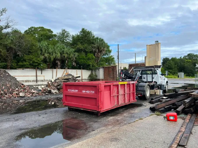 A green dumpster is parked in front of a house.