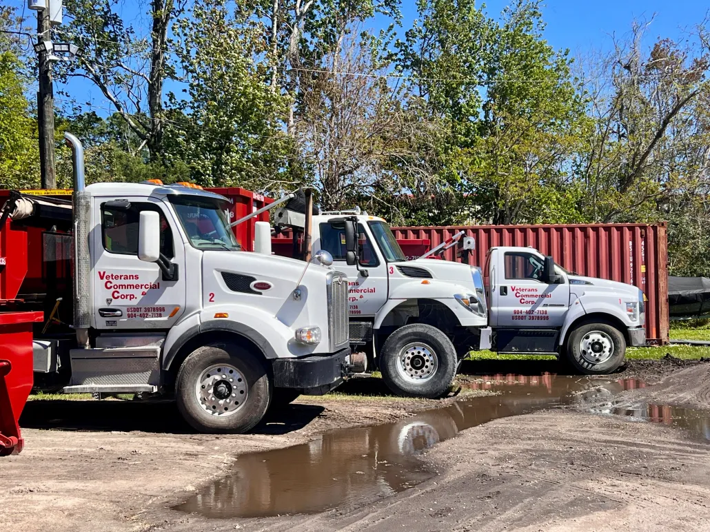 A dumpster is being towed by a tow truck in front of a house.