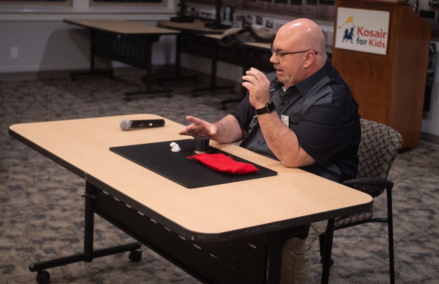 Man siting at table in black shirt performing a magic trick