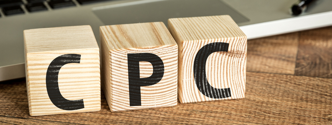 The word cpc is written on wooden blocks in front of a laptop.