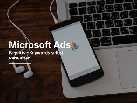 Kopfhörer und ein Handy liegen auf einem Laptop auf einem Holztisch.