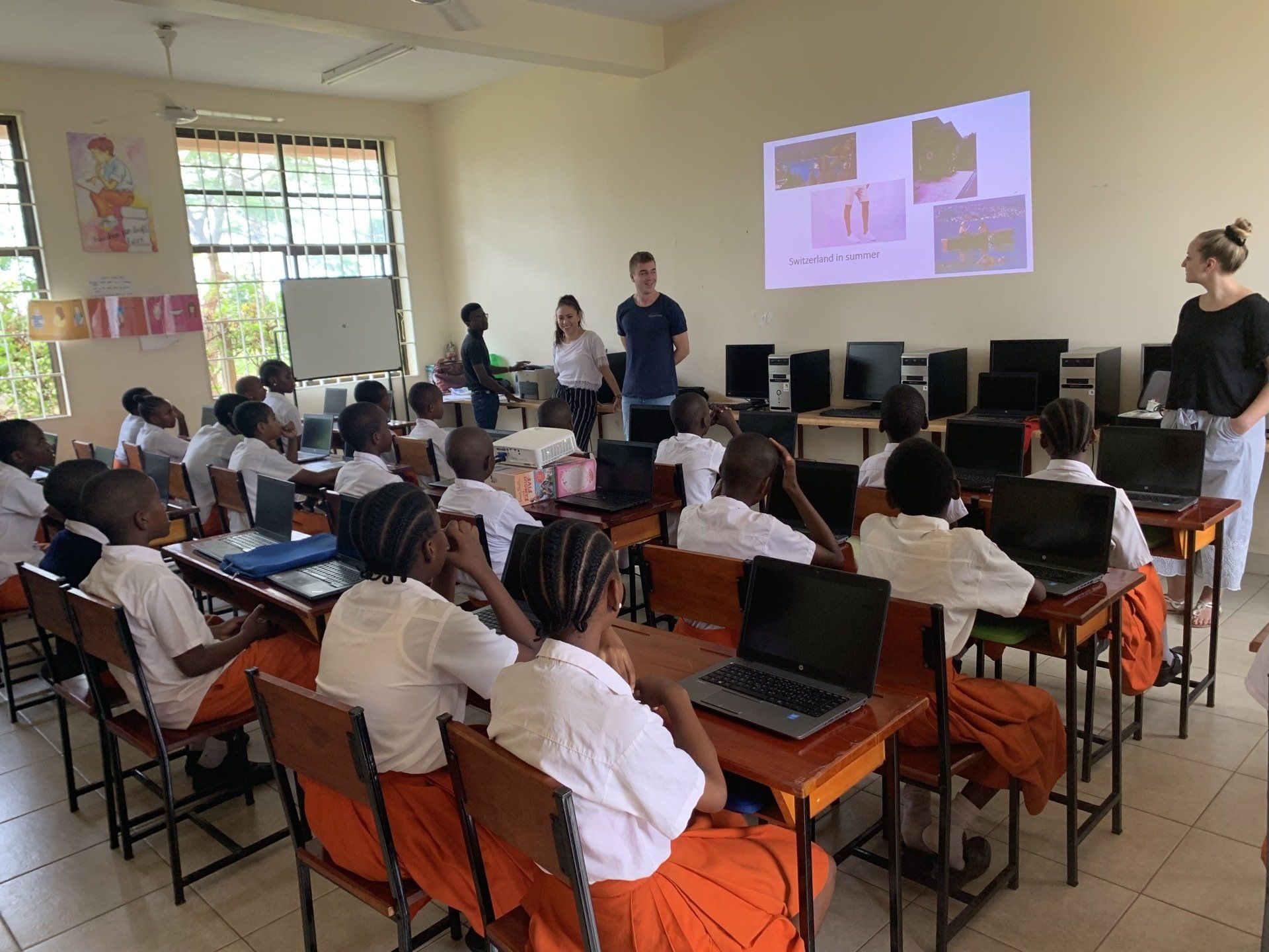 Eine Gruppe Kinder sitzt mit Laptops an Tischen in einem Klassenzimmer.