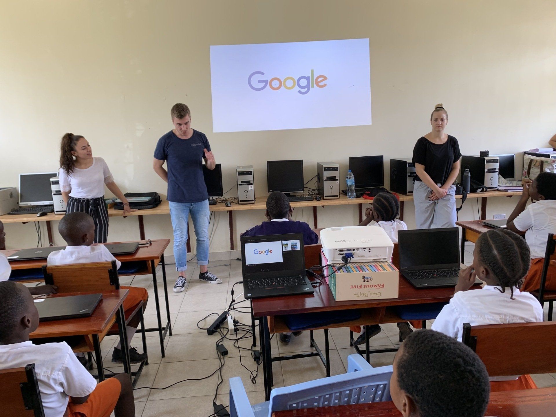 Eine Gruppe von Leuten in einem Klassenzimmer vor einem Google Schild.