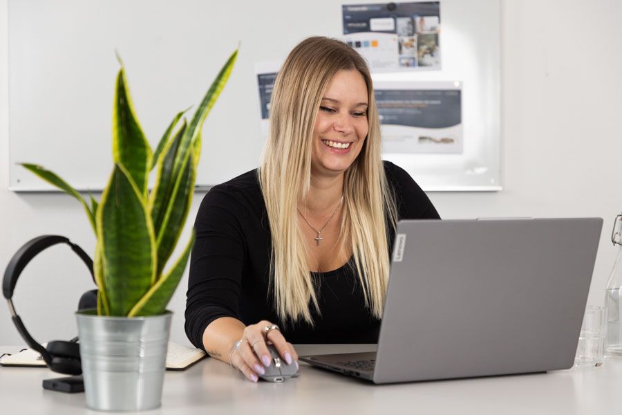 Eine Frau sitzt an einem Schreibtisch und benutzt einen Laptop.