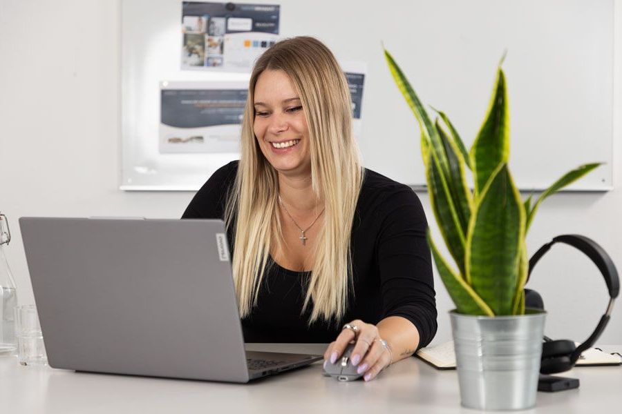 Eine Frau geht mit einem Laptop in der Hand einen Flur entlang.