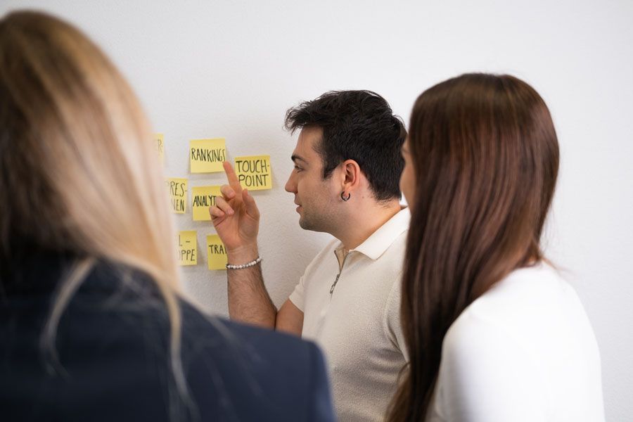 Eine Gruppe von Leuten sieht sich Haftnotizen auf einem Whiteboard an.