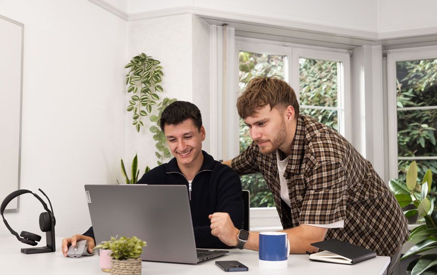 Zwei Männer schauen sich gemeinsam einen Laptop an.