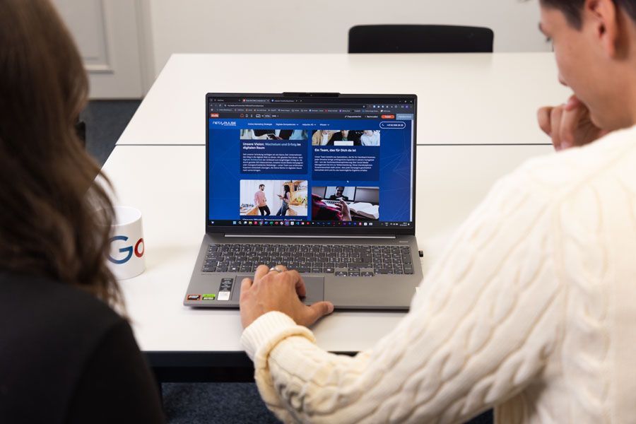 Ein Mann und eine Frau sitzen an einem Tisch und benutzen einen Laptop.