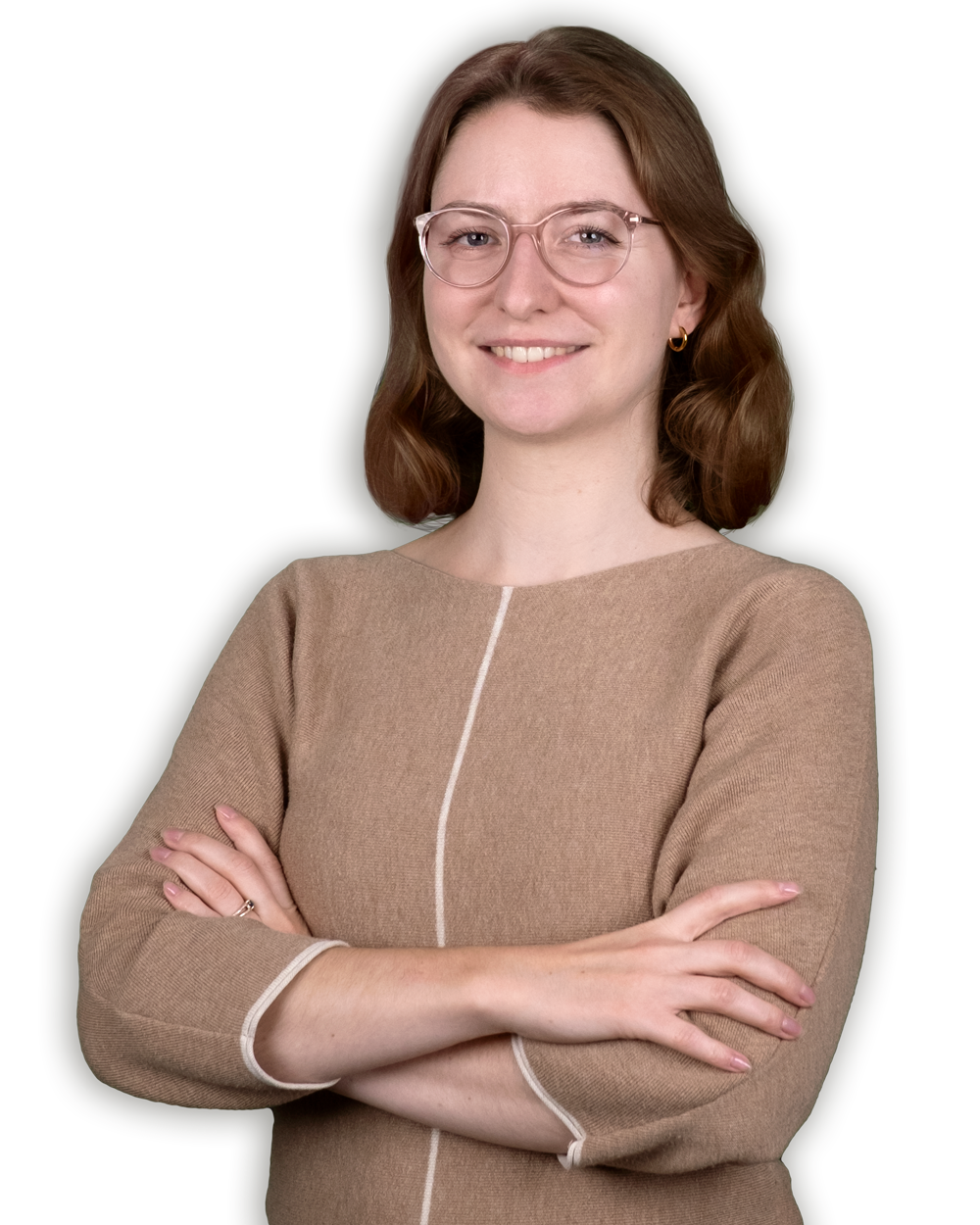Eine Frau mit Brille und braunem Pullover steht mit verschränkten Armen da.