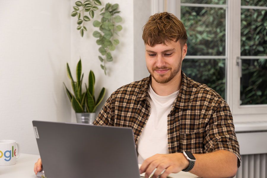 Ein Mann sitzt an einem Tisch und benutzt einen Laptop.