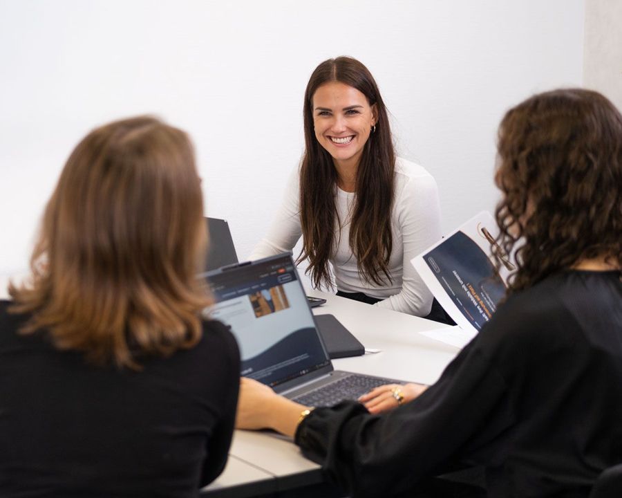 Eine Frau geht mit einem Laptop in der Hand einen Flur entlang.