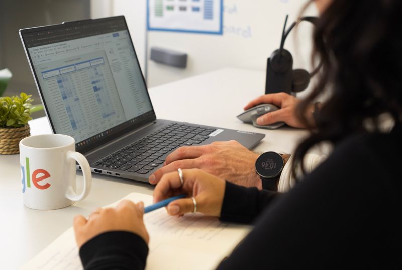 Ein Mann und eine Frau sitzen an einem Schreibtisch und benutzen einen Laptop.