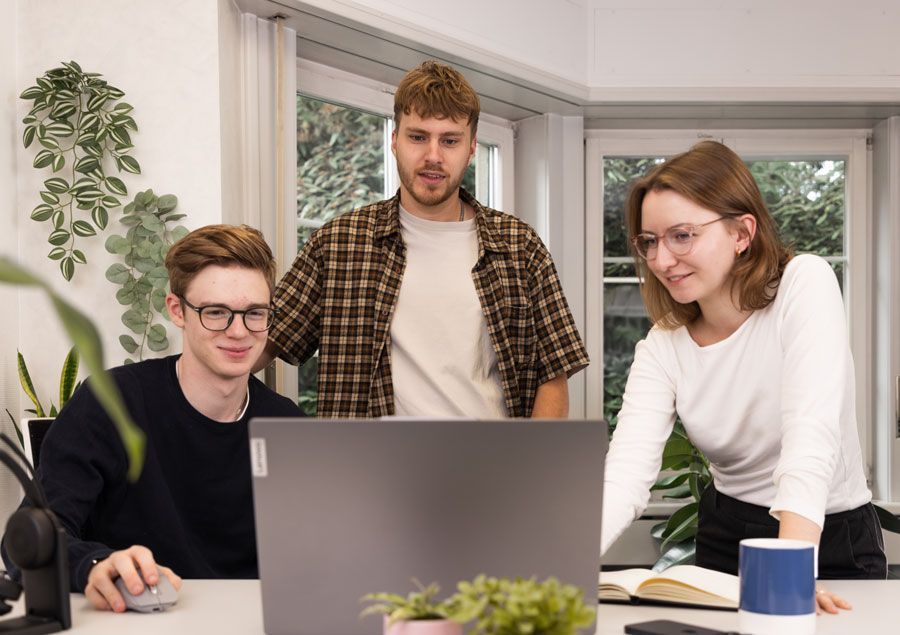 Eine Gruppe von Leuten steht um einen Laptop herum.