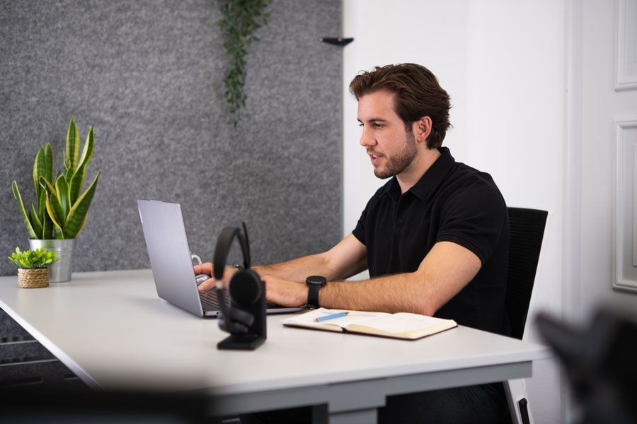 Eine Gruppe von Leuten sitzt um einen Tisch herum und schaut auf einen Laptop.