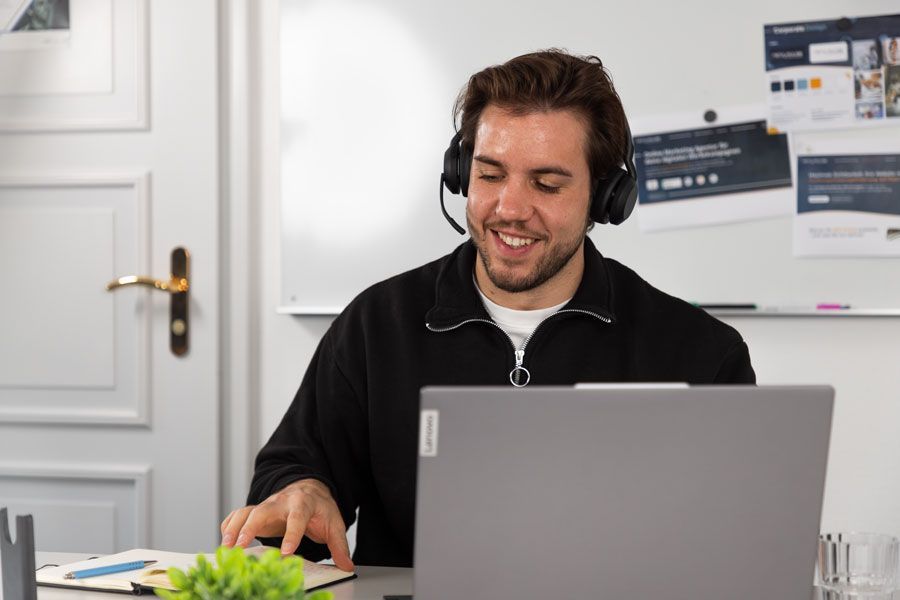 Ein Mann mit Kopfhörern sitzt vor einem Laptop.