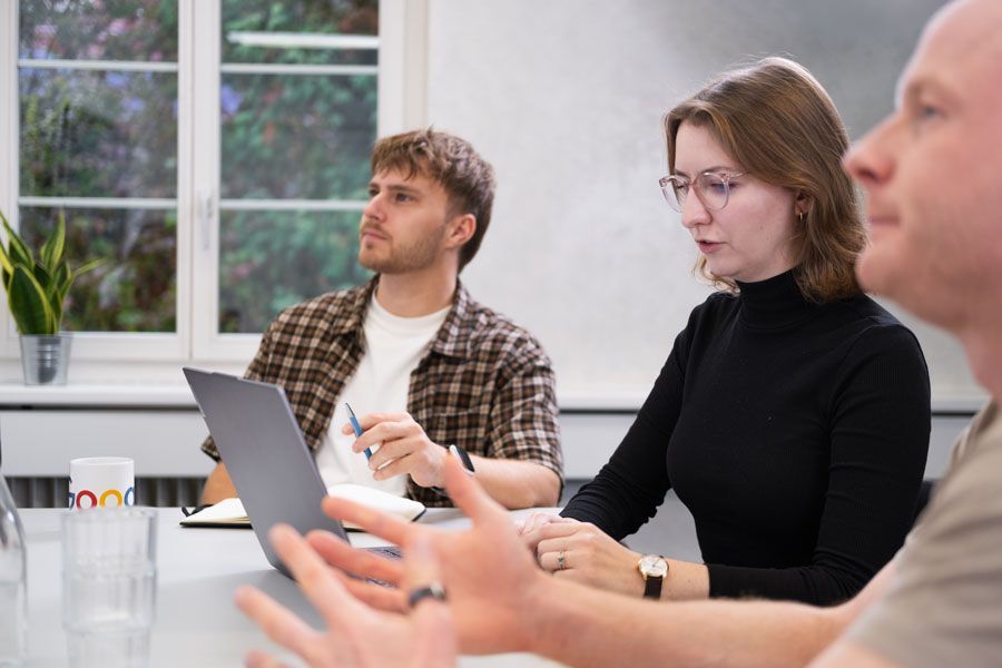 Eine Gruppe von Leuten sitzt mit einem Laptop an einem Tisch.