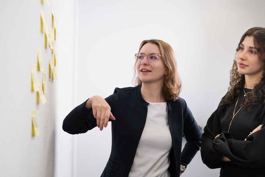 Zwei Frauen stehen nebeneinander vor einem Whiteboard.