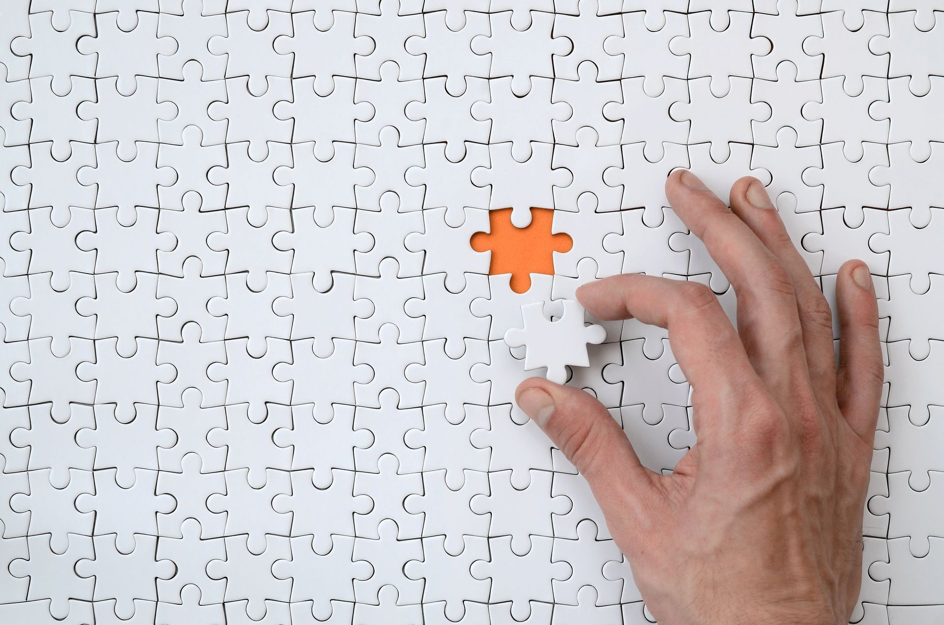 Ein Puzzle, wo ein Puzzleteil fehlt und eine Person es hinzufügt.