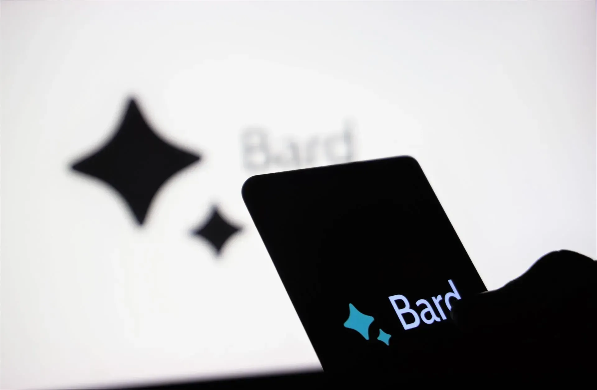 Hand, die eine Karte mit dem „Bard“-Logo vor einem Bildschirm hält, auf dem dasselbe Logo zu sehen ist.