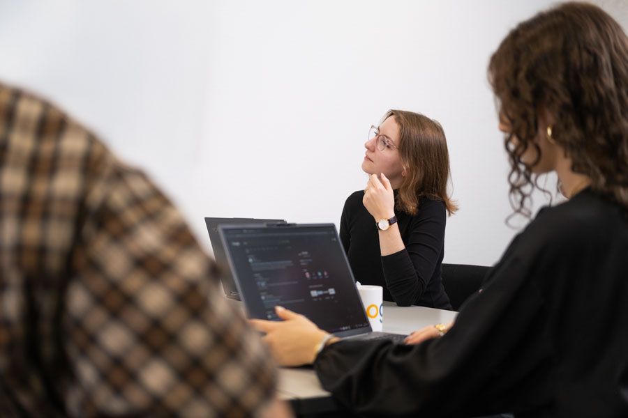 Eine Gruppe von Leuten sitzt mit Laptops an einem Tisch.