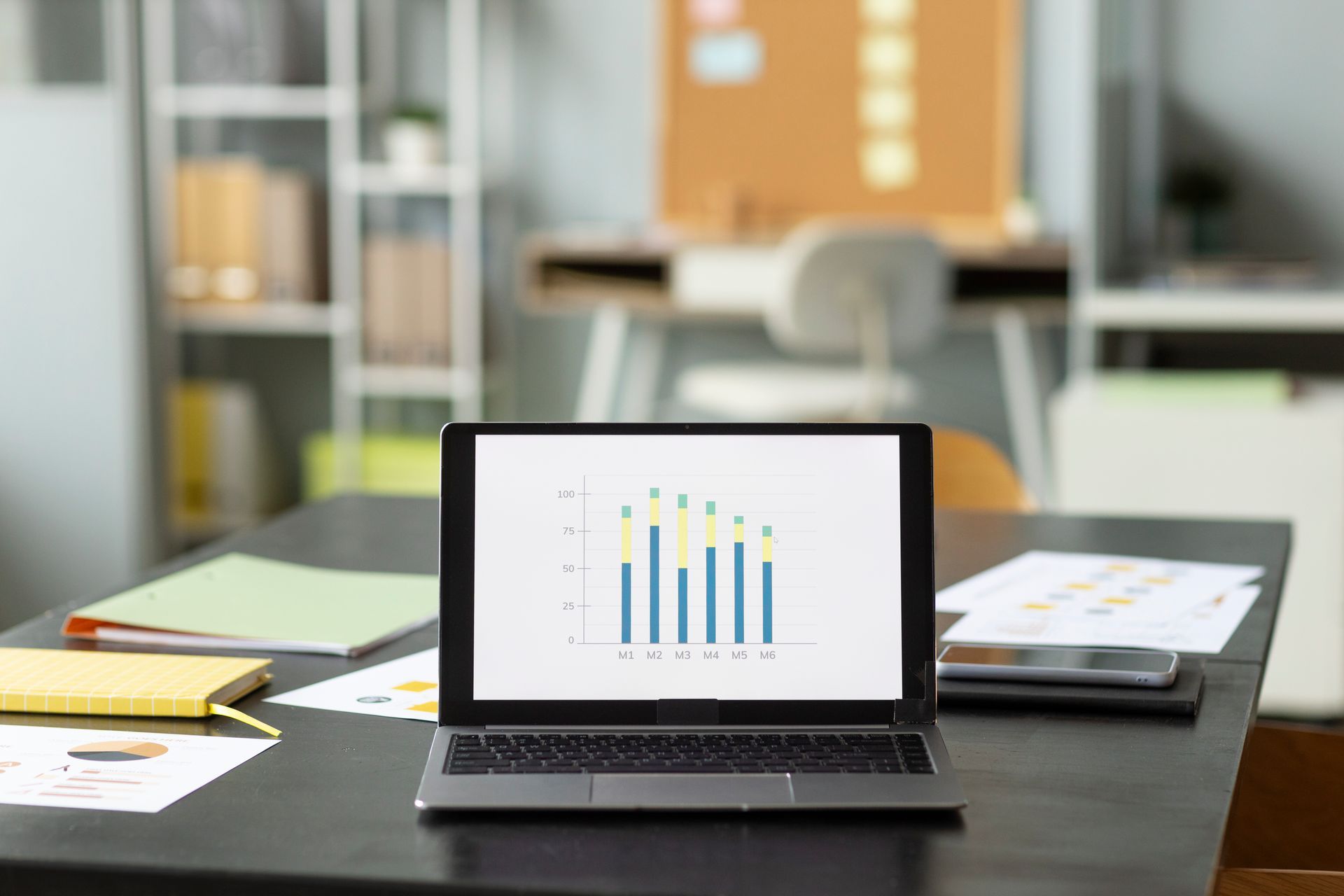 Auf einem Schreibtisch steht ein Laptop mit einer Grafik auf dem Bildschirm.