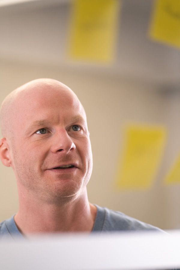 Ein Mann hinter einer Post-It-Glaswand betrachtet gelbe Post-Its