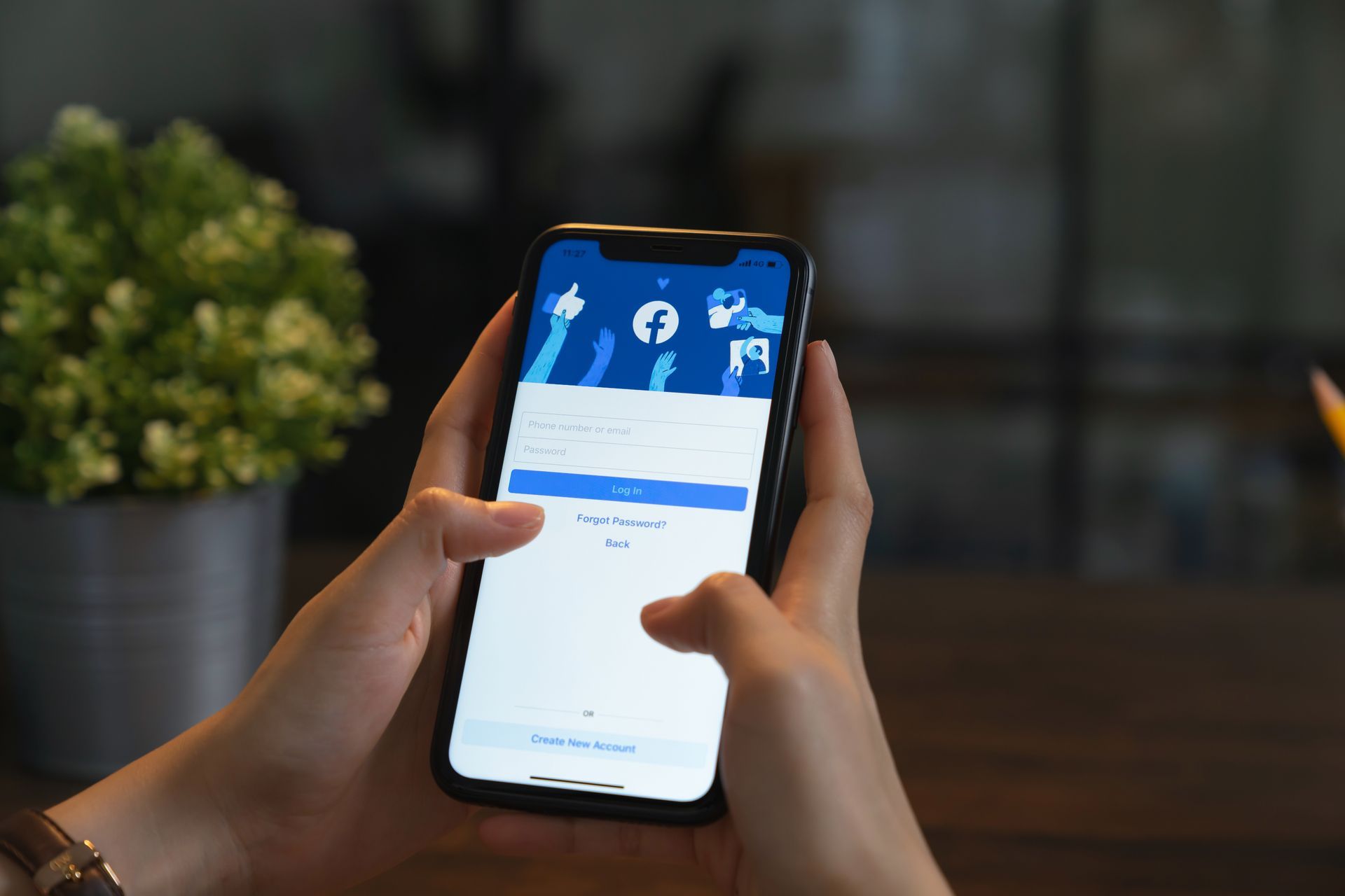 A person is holding a cell phone in their hands and using facebook.