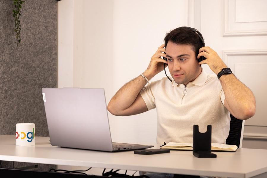 Mann mit Headset arbeitet an einem Laptop an einem Schreibtisch.
