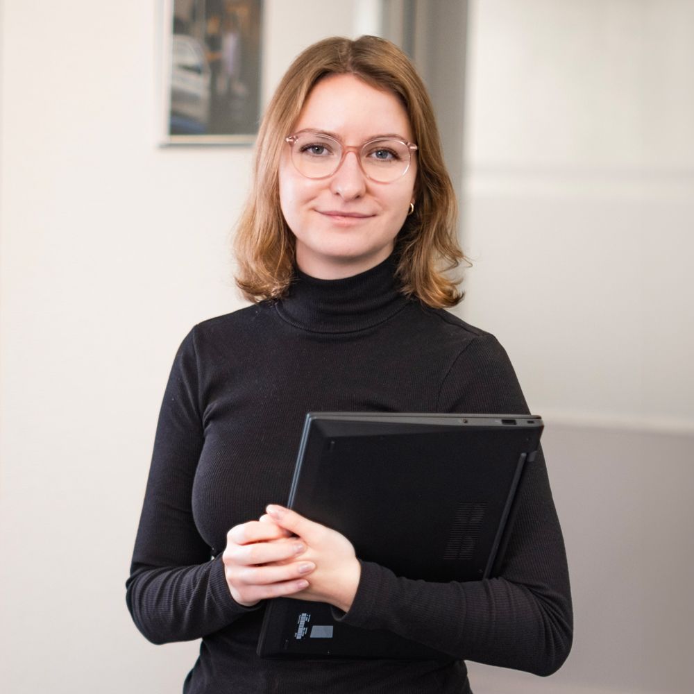 Eine Frau im schwarzen Rollkragenpullover hält ein Tablet