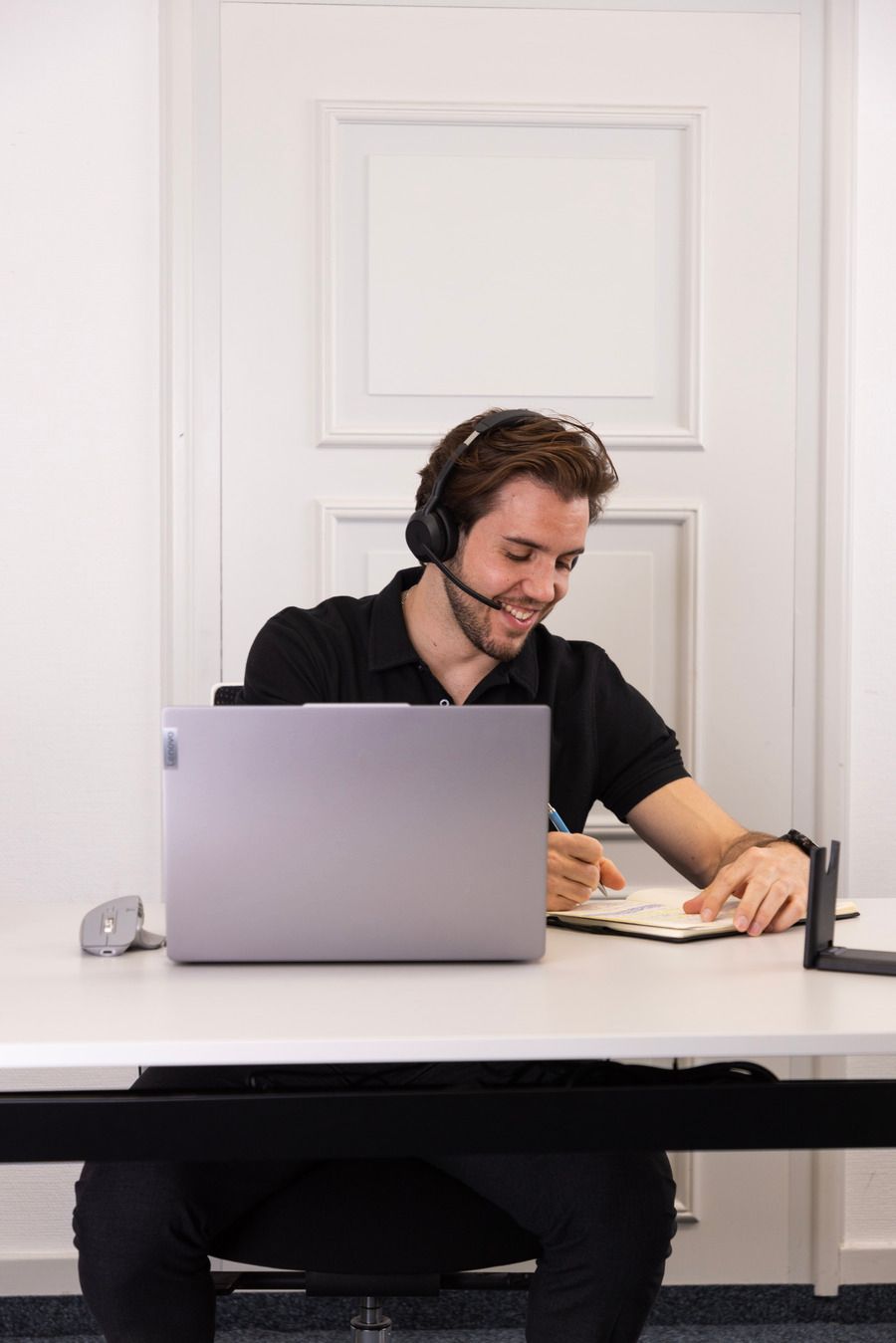 Eine Frau sitzt an einem Tisch und benutzt einen Laptop in einem Meeting.