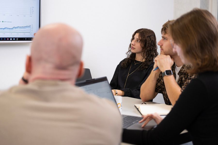 Eine Gruppe von Leuten sitzt mit Laptops um einen Tisch.