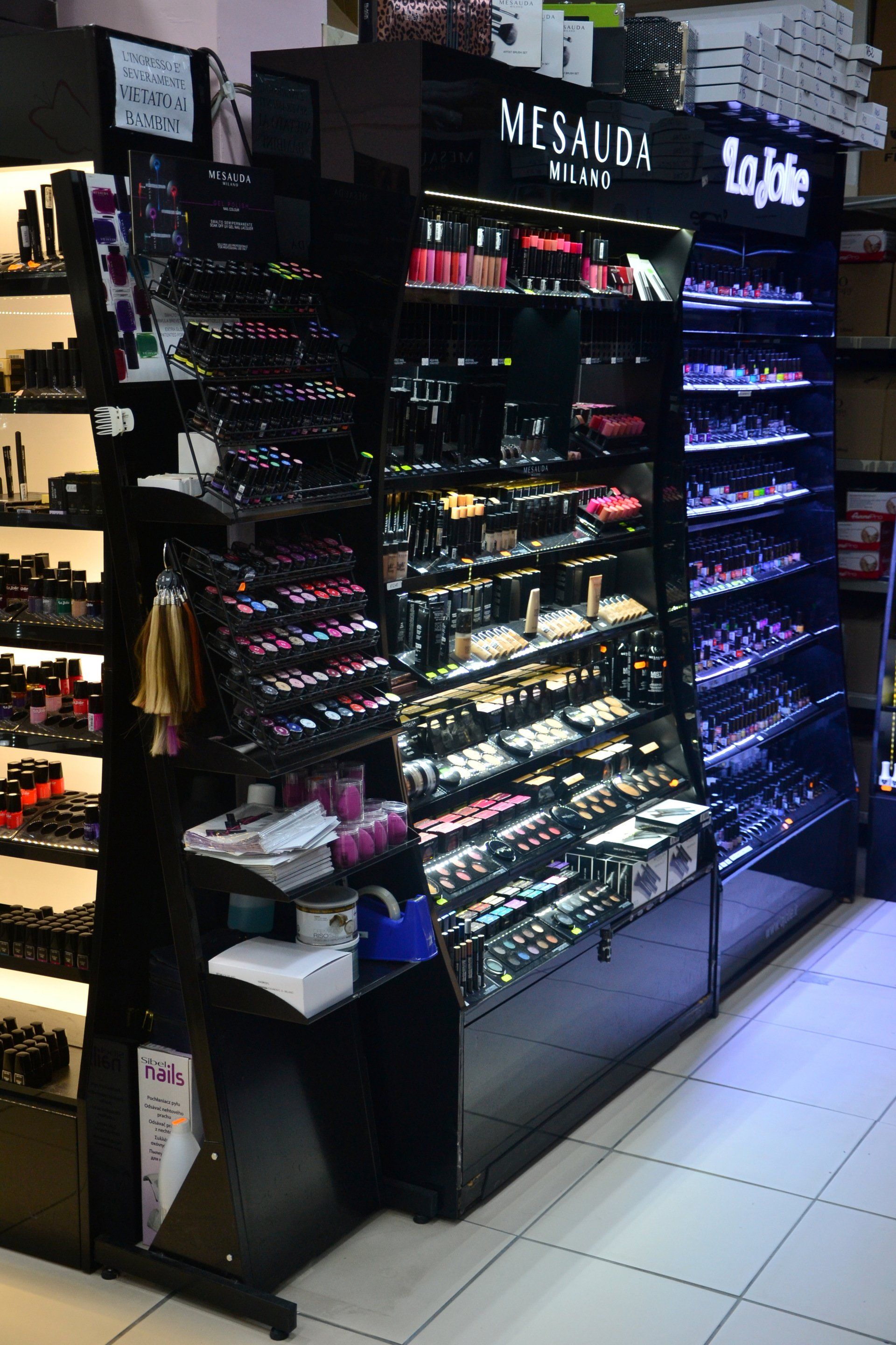 Esposizione di cosmetici con smalti, rossetti e prodotti per il trucco in un negozio.