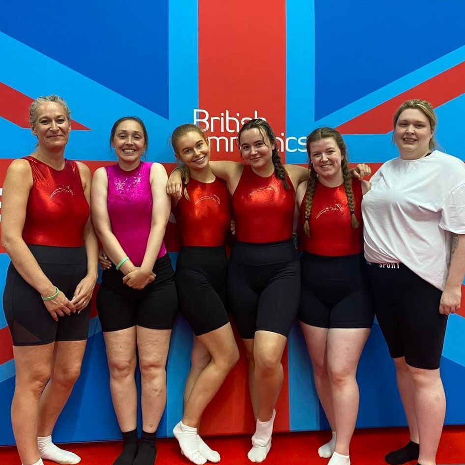 A group of women are posing for a picture in front of a british flag.