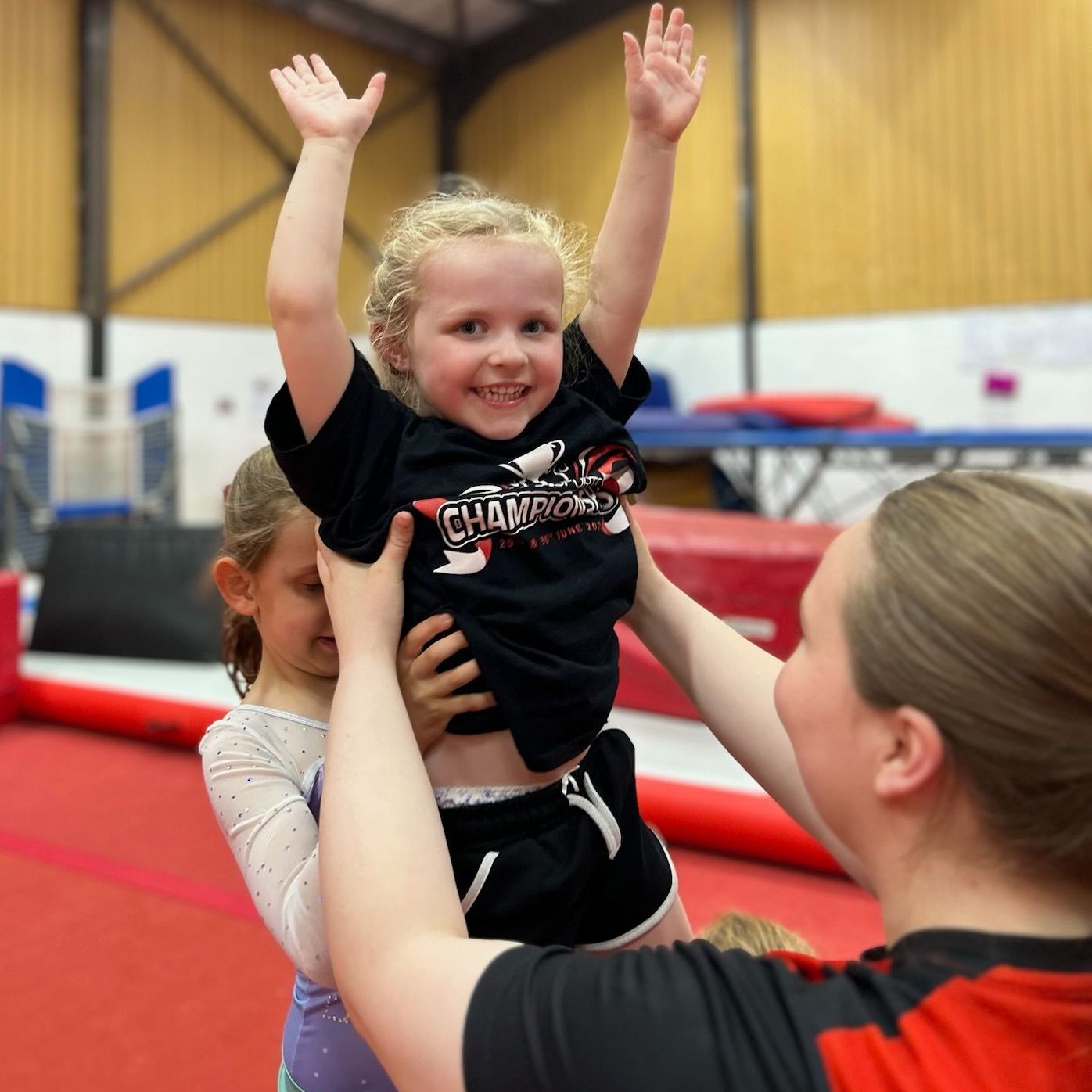 A woman is holding a little girl who is wearing a shirt that says champions