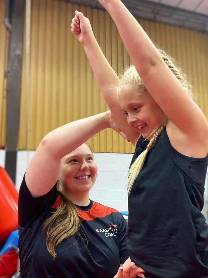 Two women are standing next to each other with their arms in the air.