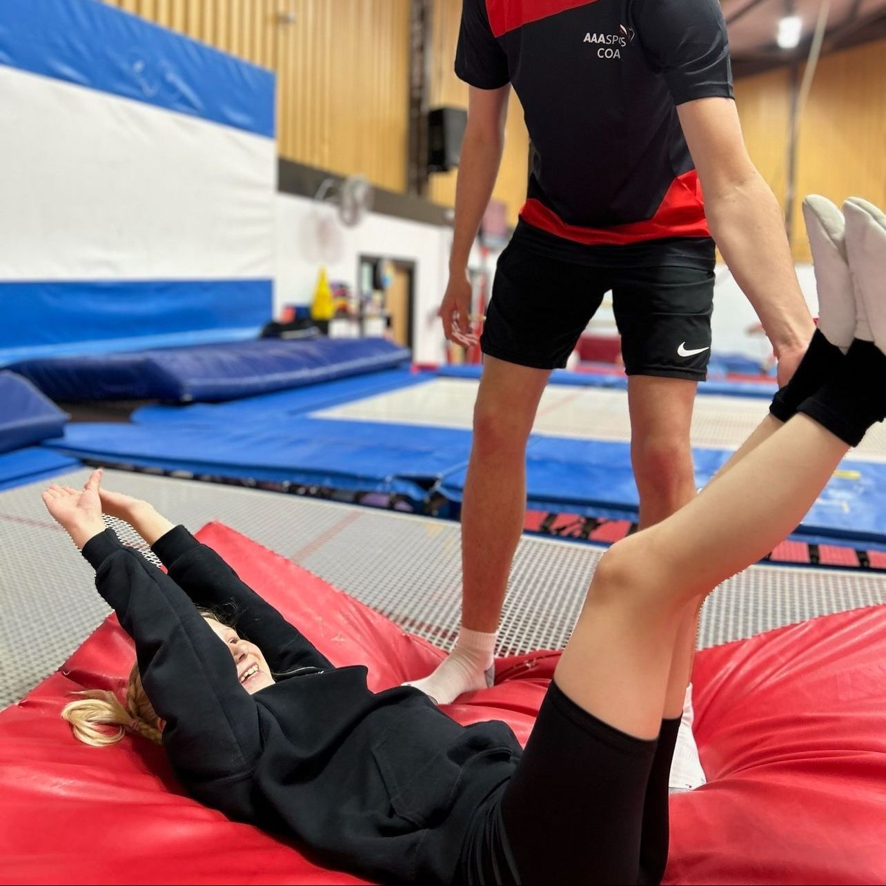 A woman is laying on a red mat while a man stands behind her