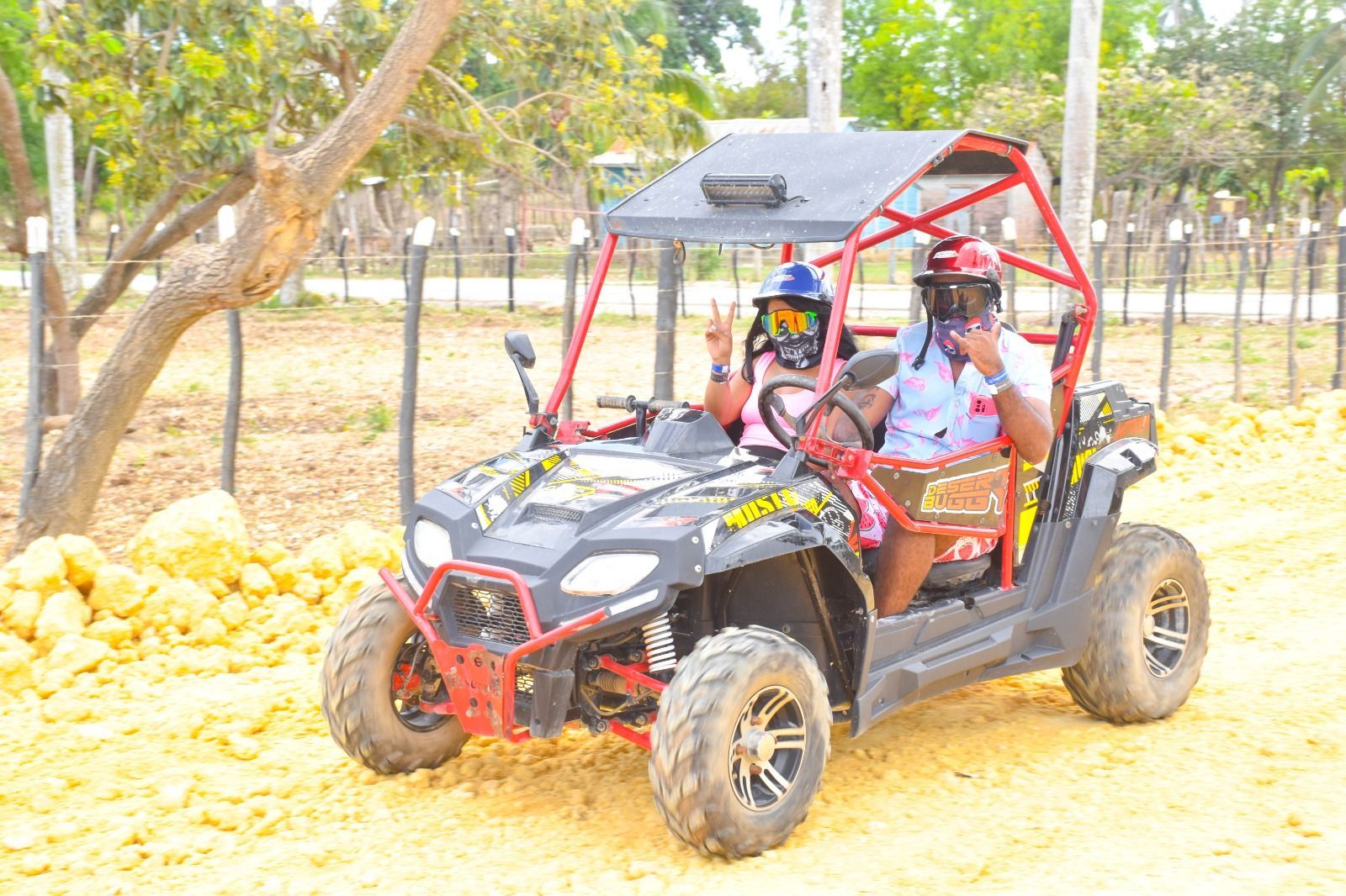 Two people driving a dune buggy through the rugged terrain in Punta Cana, enjoying an exciting and dusty adventure.