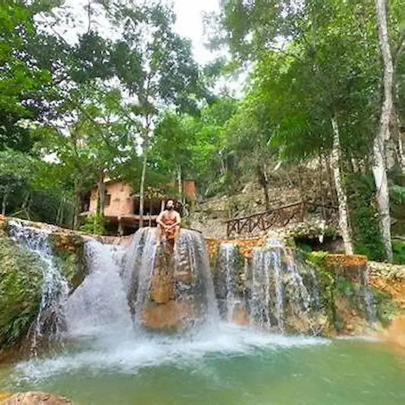 Person enjoying the natural waterfalls of Caño Hondo surrounded by tropical vegetation in Miches, Dominican Republic