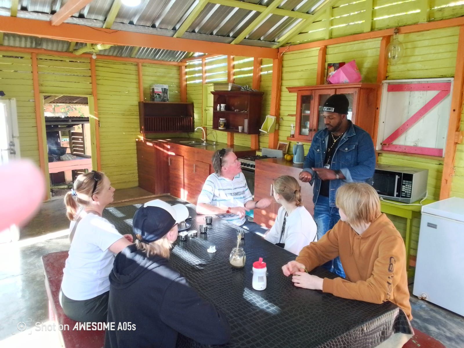 Turistas disfrutando de una demostración en una cocina típica dominicana, aprendiendo sobre la cultura y gastronomía local.