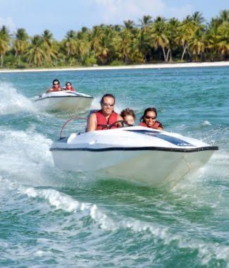 Family enjoying a thrilling speed boat tour in Punta Cana, gliding over the crystal-clear waters with palm-lined beaches in the background