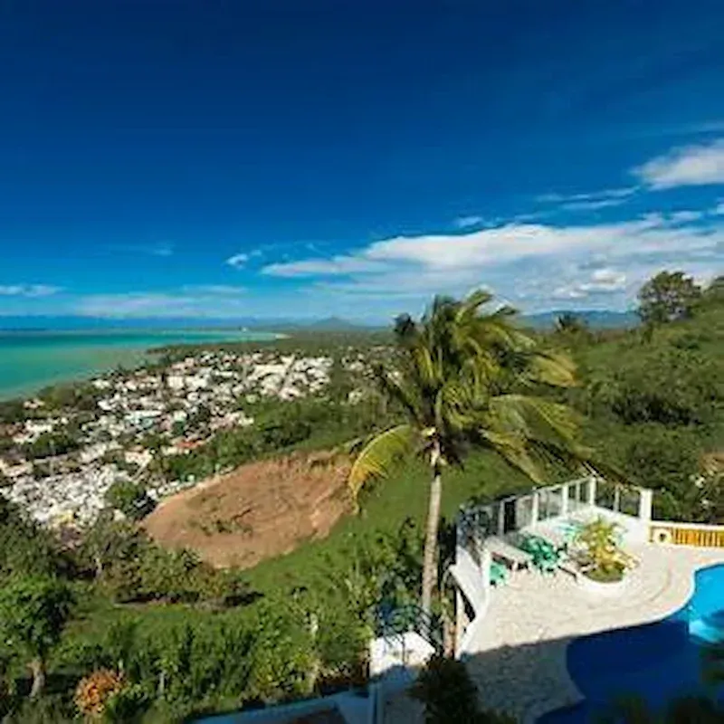 Panoramic view of the town of Miches with the ocean in the background and a terrace with a pool surrounded by lush vegetation in the Dominican Republic
