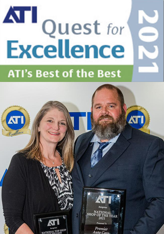 A man and a woman are posing for a picture in front of a sign that says ati quest for excellence